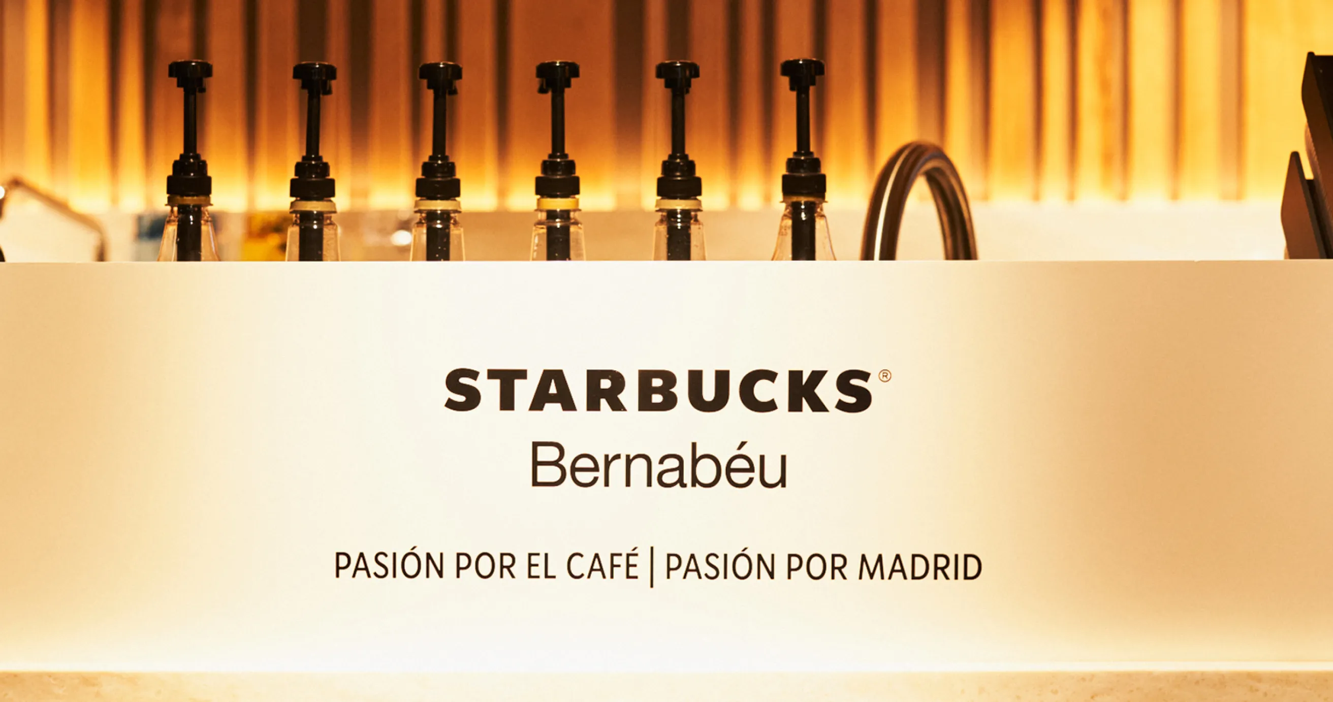 Imagen de logo de Starbucks con el Claim "Pasión por el Café, pasión por Madrid", de fondo se ven elementos para preparar bebidas
