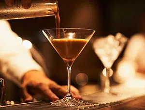Imagen de un barista sirviendo un espresso martini en copa de cristal