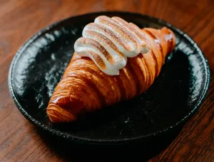 Foto de un croissant en un plato negro con una crema