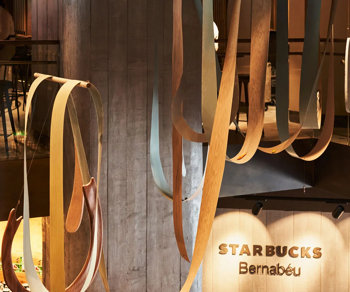 Imagen de la escultura de madera y de fondo el logo de Starbucks Bernabeu