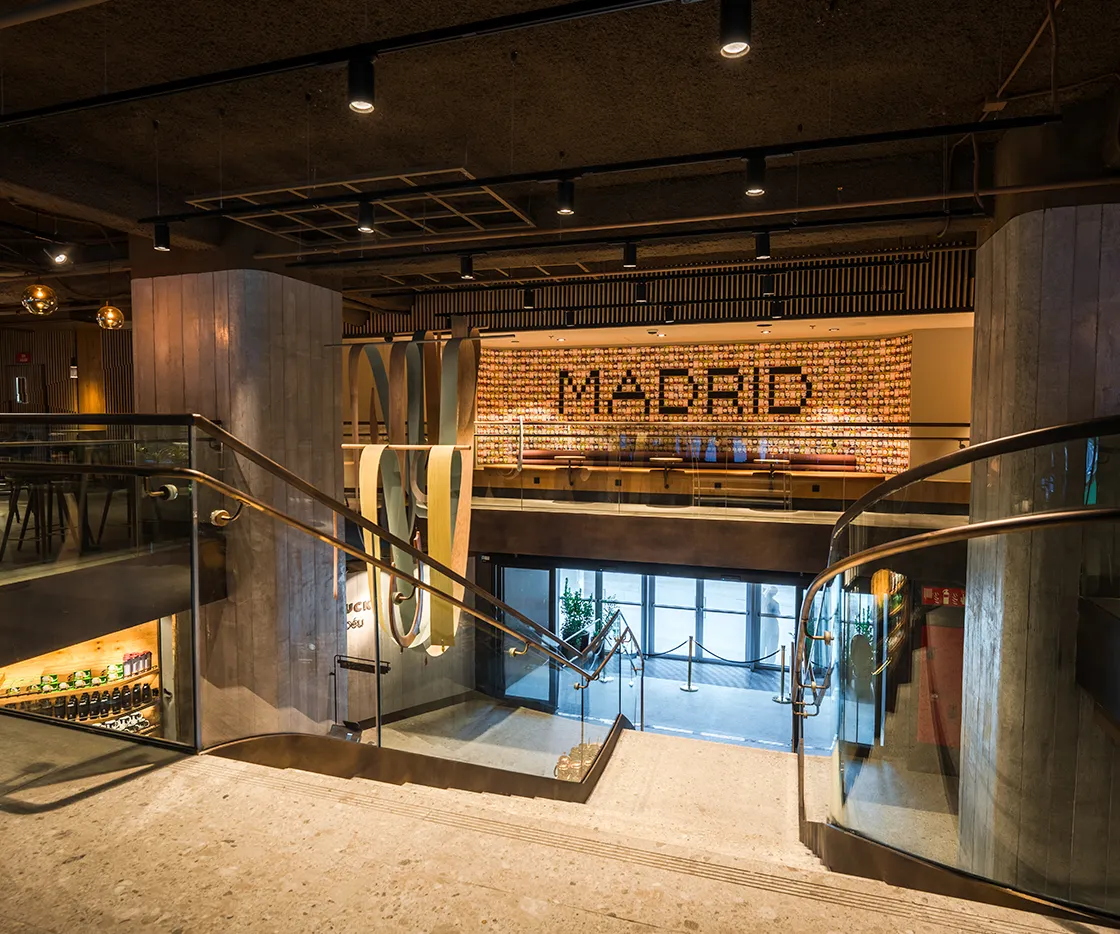 Imagen de la escalera que sube a la segunda planta de la tienda. Se ve la escultura y la palabra Madrid de fondo