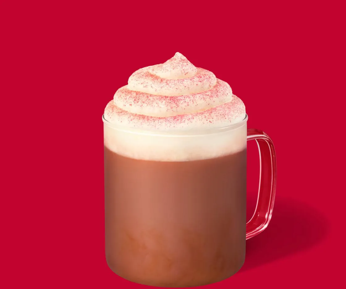 Red Velvet Latte caliente con nata en una tasa de vidrio, sobre un fondo rojo
