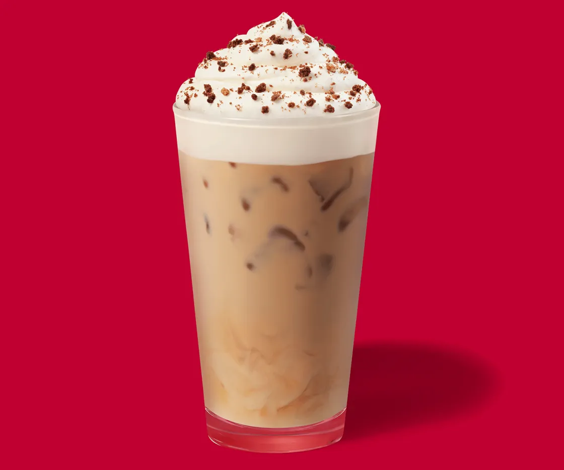 Iced Caramel Cookie Latte en un vaso de vidrio con fondo rojo