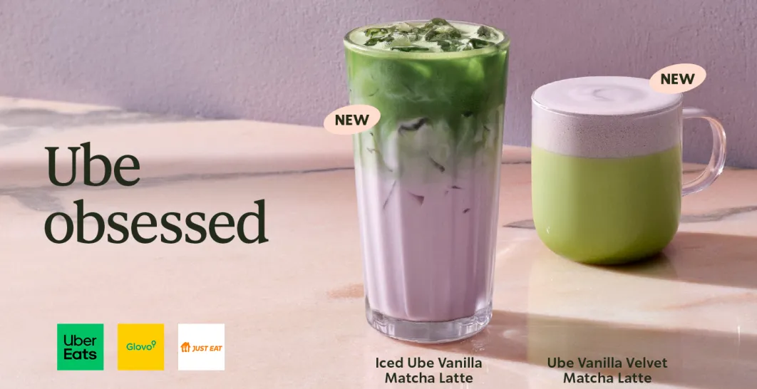 dos ube vanilla matcha lattes, uno frio y uno caliente sobre una mesa con fondo morado